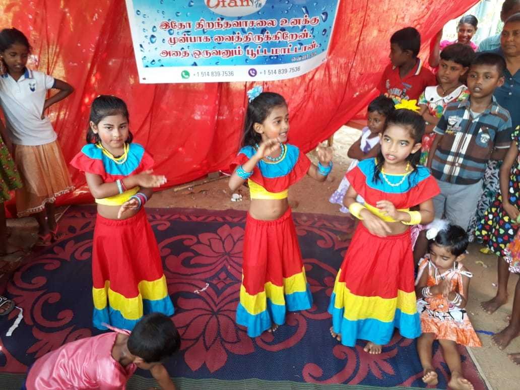Children performing at a community gathering beneath a GFAN banner